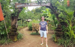 Pemula Bali Farm Cooking School. Ich stehe am Eingangstor. Auf dem Balken darüber steht: Balinese Farm Cooking School