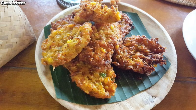 Bali Farm Cooking. Corn fritters served on a banana leaf on a wooden board.