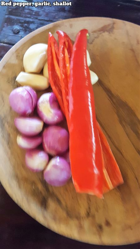 Bali Farm Cooking School. Red pepper, garlic and shallot on a wooden plate.