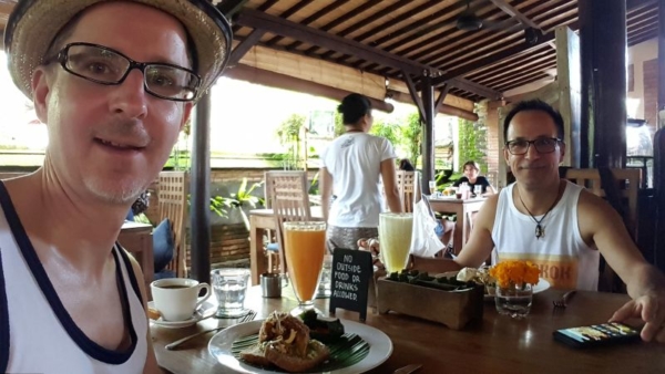 Bali Buda. Breakfast. José and I at breakfast. Set table with Smashed Avocado, fresh juices (papaya and pineapple), coffee and water.