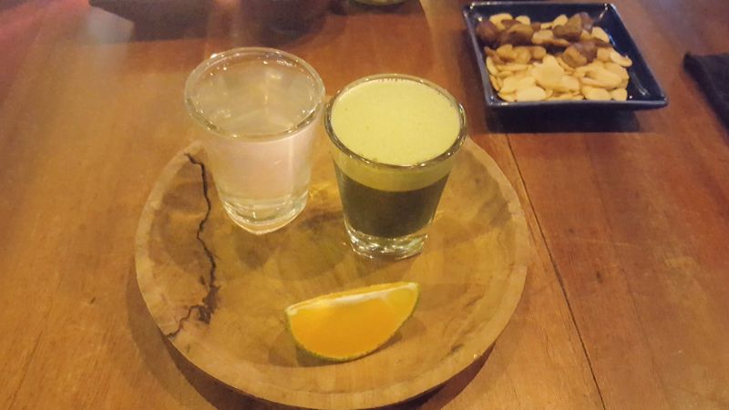 Cafe Vida Canggu. Wheatgrass shot with a piece of lemon and a glass of coconut water for rinsing.