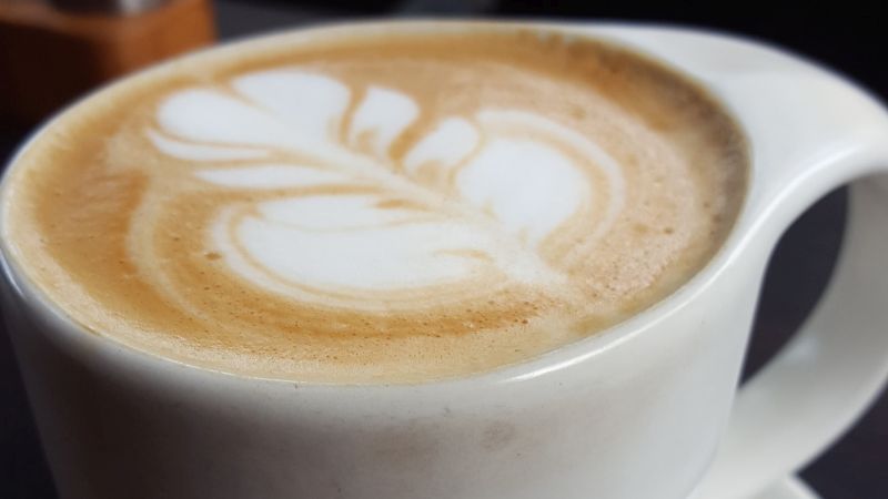 Essen in Ubud. Mudra Café. Kaffee Latte mit schönem floralen Muster im Milchschaum.