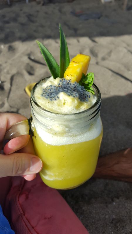 The Paluh Surf and Cafe. Pineapple juice. In a glass with handle. Decorated with mint, a pineapple slit and passion fruit pulp.