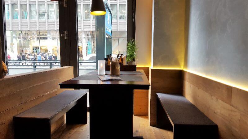 Peter Pane interior. Wooden benches and table, cosy light supported by indirect lighting.